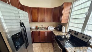A kitchen with wooden cabinets, a stainless steel refrigerator, a stove, and a sink. - Amazing Caribbean views! (BO Lujan,)
