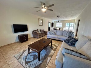 A spacious living room with a flat-screen TV, two sofas, a coffee table, and a ceiling fan. - Amazing Caribbean views! (BO Lujan,)