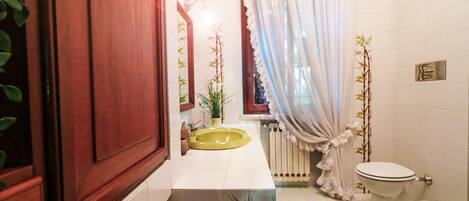 A bathroom with a yellow sink, white toilet, and a green rug.