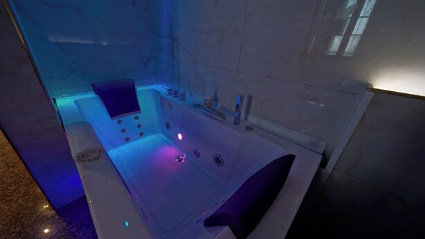 Ein modernes Badezimmer mit einer großen Badewanne, einer Duschkabine aus Glas und einer Wand mit Marmorplatten.