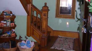 Una escalera con barandilla de madera, un candelabro, un espejo y un árbol de Navidad.