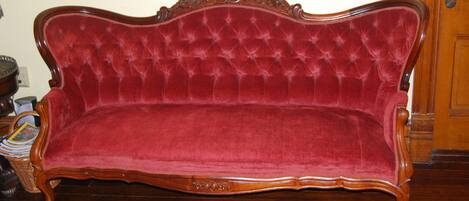 A red velvet sofa with a wooden frame and ornate carvings.