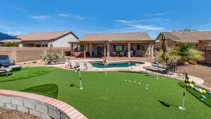 A residential property with a swimming pool, a backyard with artificial grass, and a patio area with outdoor furniture.