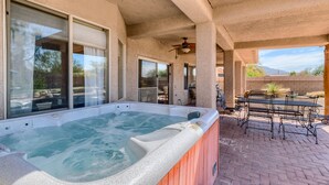 A hot tub area with a patio, outdoor seating, and a view of the surrounding landscape.