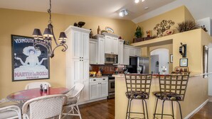 A kitchen with white cabinets, a microwave, and a dining area with wicker chairs and a red table.