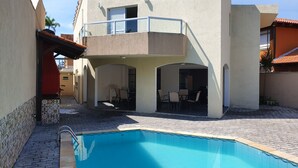 Un bâtiment à deux étages doté d’une piscine, d’un espace extérieur aménagé et d’un balcon.