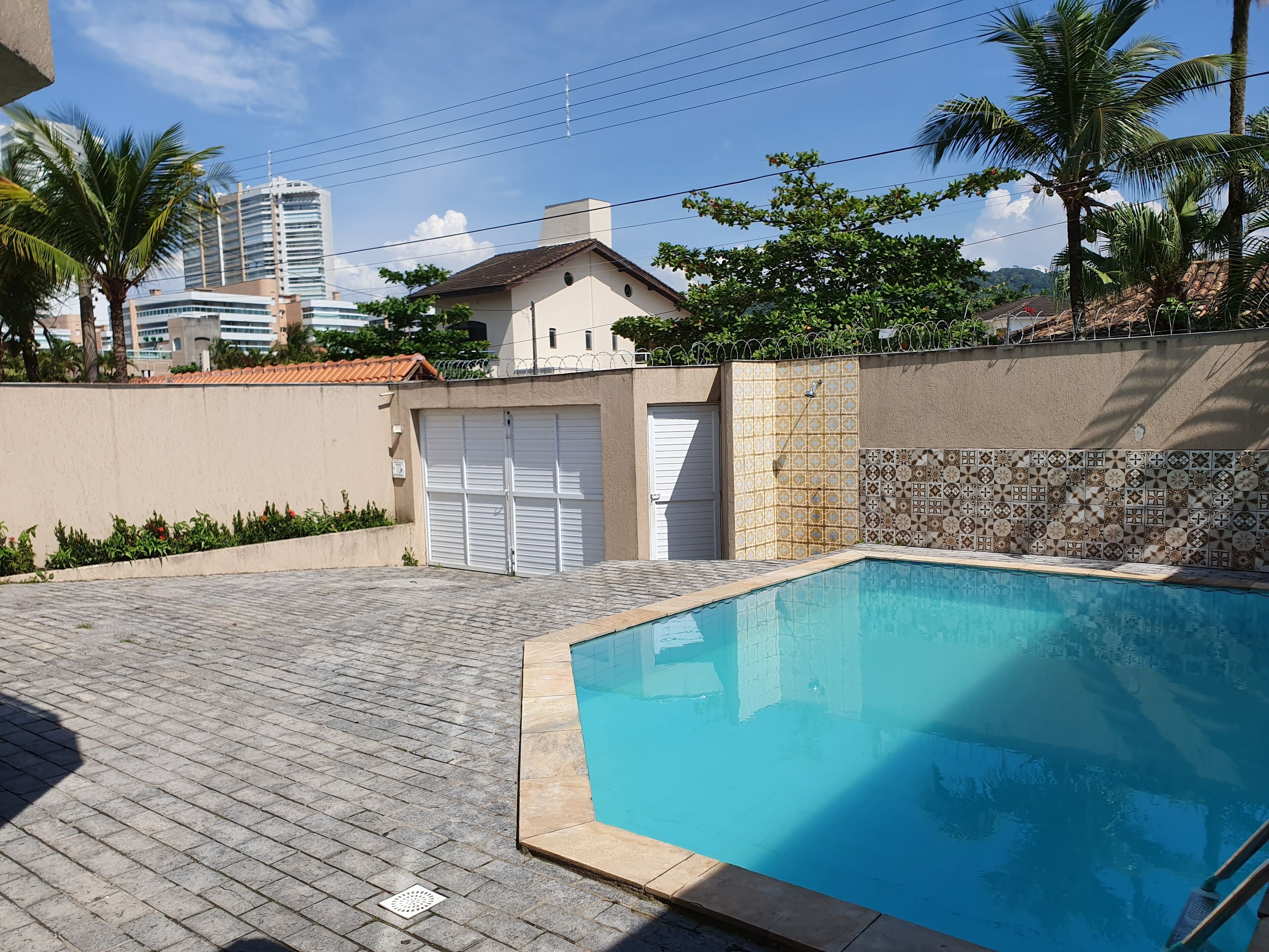 A swimming pool with a tiled edge, surrounded by a paved patio and a low wall with decorative tiles.