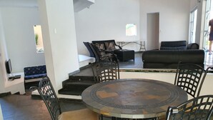 Un salon moderne avec une table ronde, des chaises noires, un canapé et un escalier menant à un niveau supérieur.