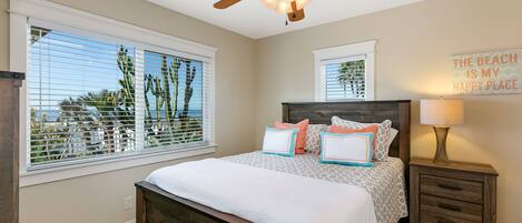 A bedroom with a bed, a ceiling fan, a nightstand, a lamp, and a window with blinds.