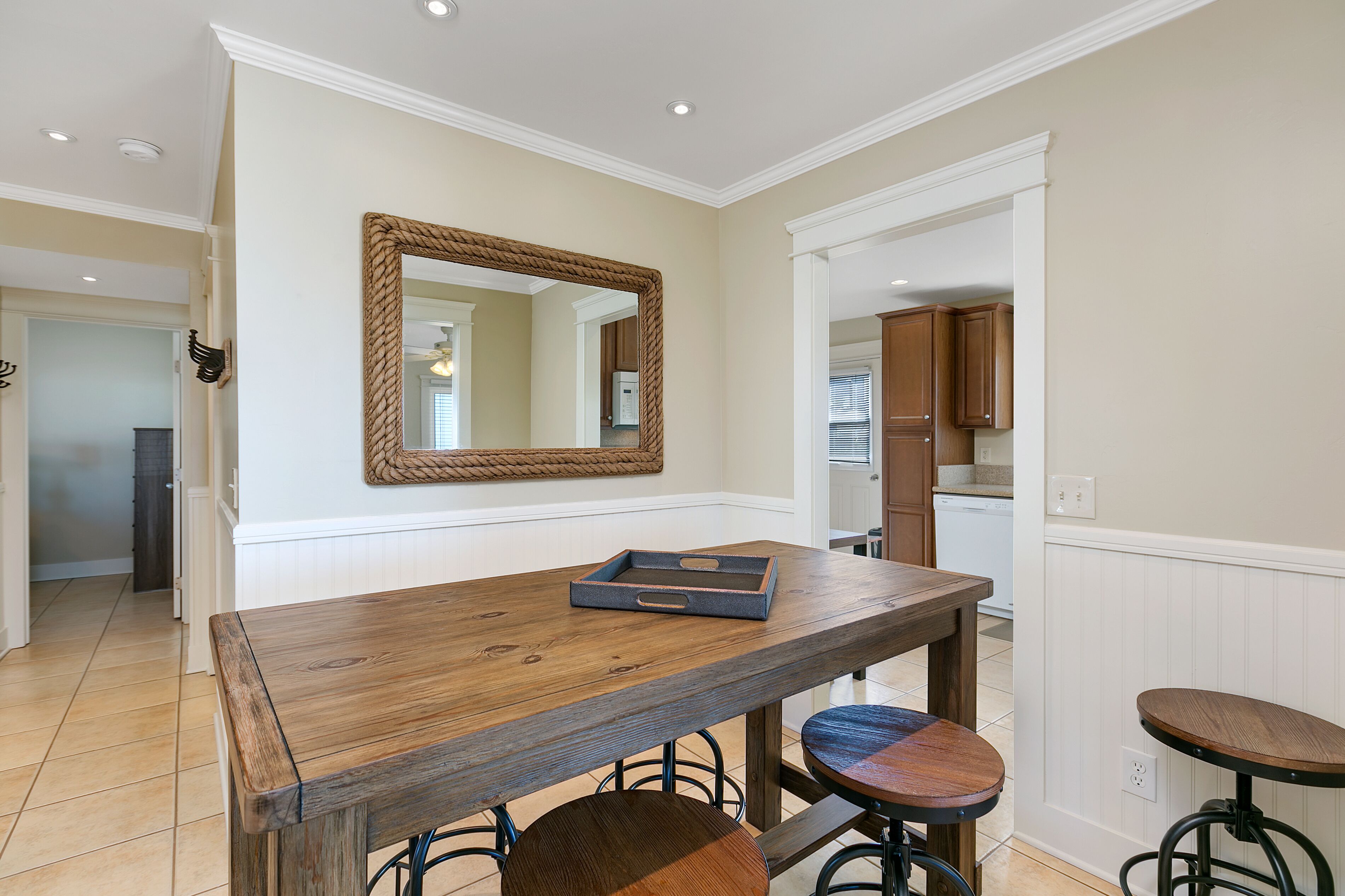 Un comedor con una mesa de madera, sillas y un espejo en la pared.