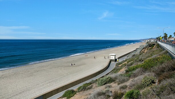 A beach with a curved walkway, a lifeguard tower, and a clear blue sky. - Carlsbad Cottage by the Beach (Carlsbad)