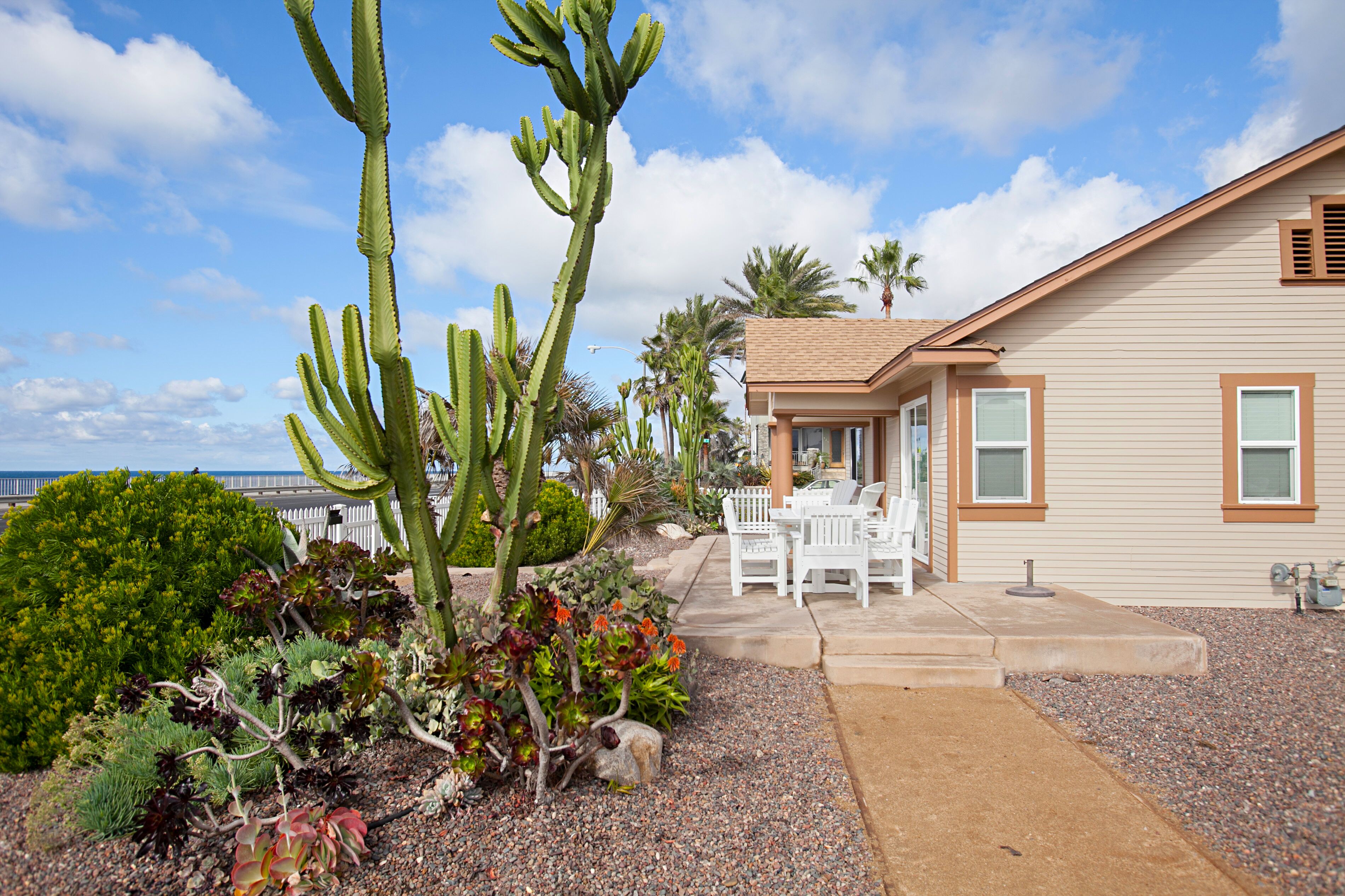 A house with a patio area featuring outdoor furniture and a variety of plants, including a prominent cactus.