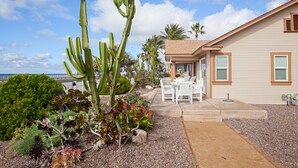 A house with a patio area featuring outdoor furniture and a variety of plants, including a prominent cactus. - Carlsbad Cottage by the Beach (Carlsbad)