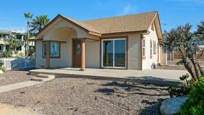A single-story house with a beige exterior, a brown roof, and a front porch. - Carlsbad Cottage by the Beach (Carlsbad)