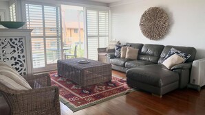 A living room with a sofa, two wicker chairs, a coffee table, and a patterned rug. - Barefoot, 7/44 Marine Drive - Fabulous Fingal Bay (Fingal Bay)