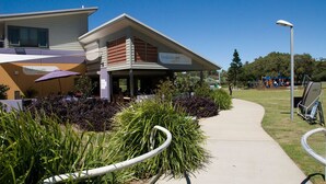 A longboat cafe with outdoor seating and a pathway leading to a playground. - Barefoot, 7/44 Marine Drive - Fabulous Fingal Bay (Fingal Bay)