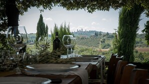 A table set for dining with a view of a vineyard and distant buildings. - Top Location - Villa in San Gimignano, Top View, 4 DBL En-Suite, Pool, AC, WiFi (San Gimignano)