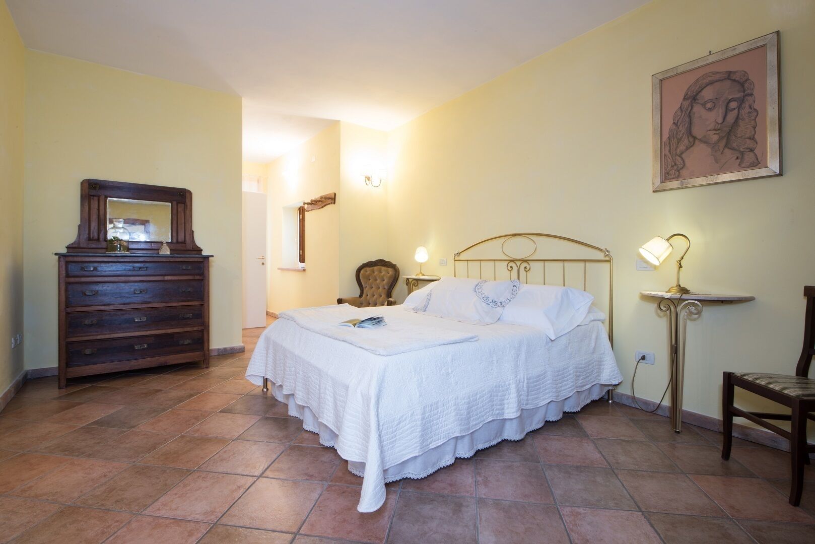 Une chambre à coucher avec un lit, une commode, une chaise et un tableau accroché au mur.