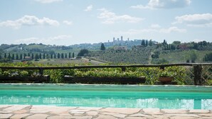 A pool with stone tiles, surrounded by greenery and a wooden fence. - Top Location - Villa in San Gimignano, Top View, 4 DBL En-Suite, Pool, AC, WiFi (San Gimignano)