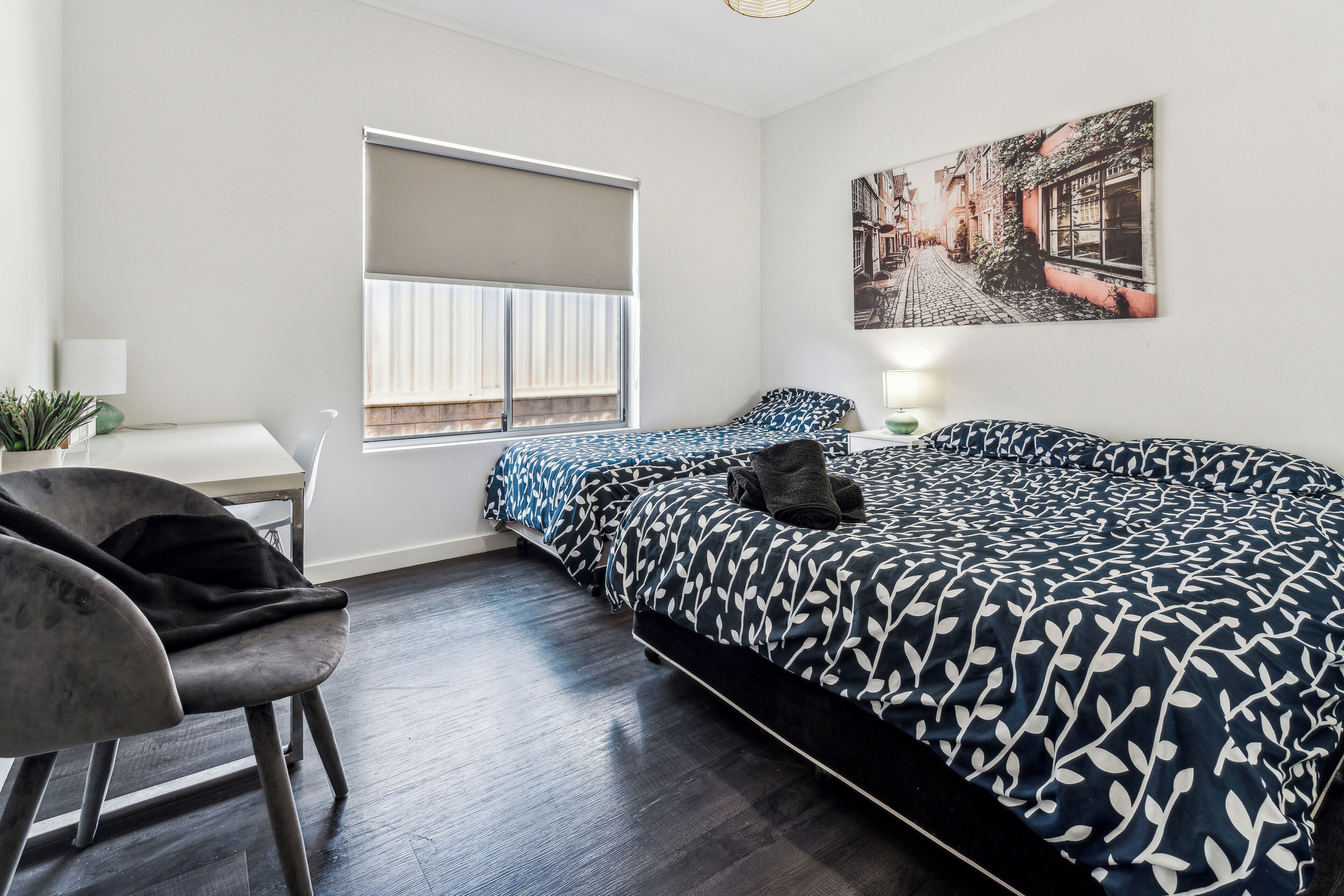 A modern bedroom with a large bed, a desk, and a chair.