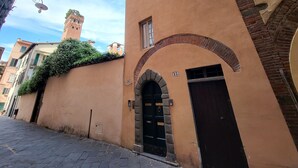 Une rue étroite, avec un bâtiment doté d’une entrée en arc de cercle et d’une tour en arrière-plan.