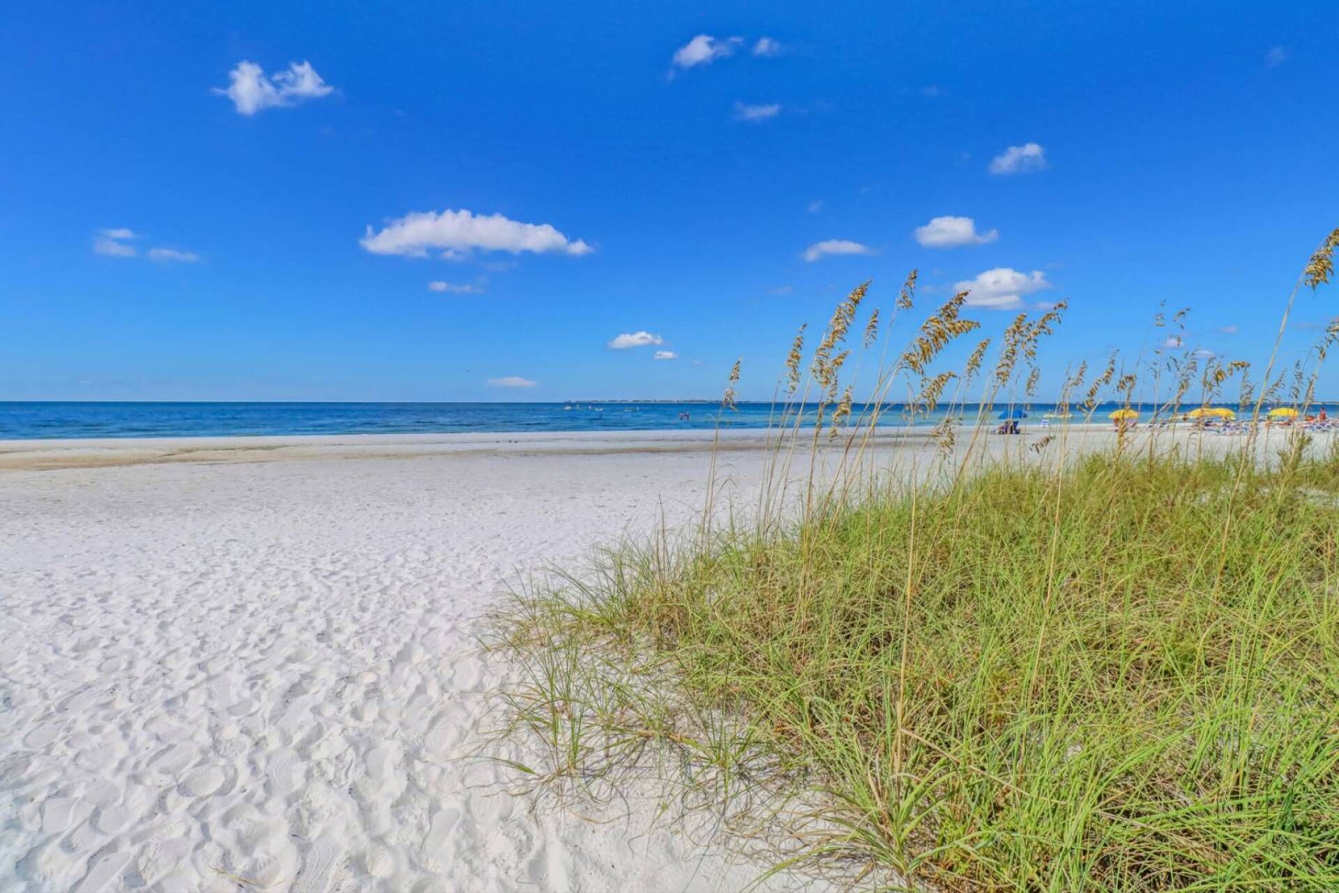 Ein Sandstrand mit blauem Himmel und weiter Meereslinie.