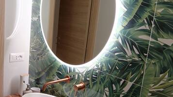 A bathroom with a round mirror, wooden vanity, and a sink.