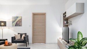 Una sala moderna con un sofá, una mesa de centro, un televisor y una puerta.