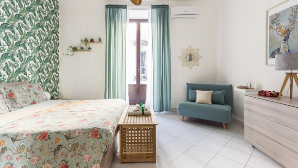 Un dormitorio con cama, sofá, mesita de noche de madera y cómoda.