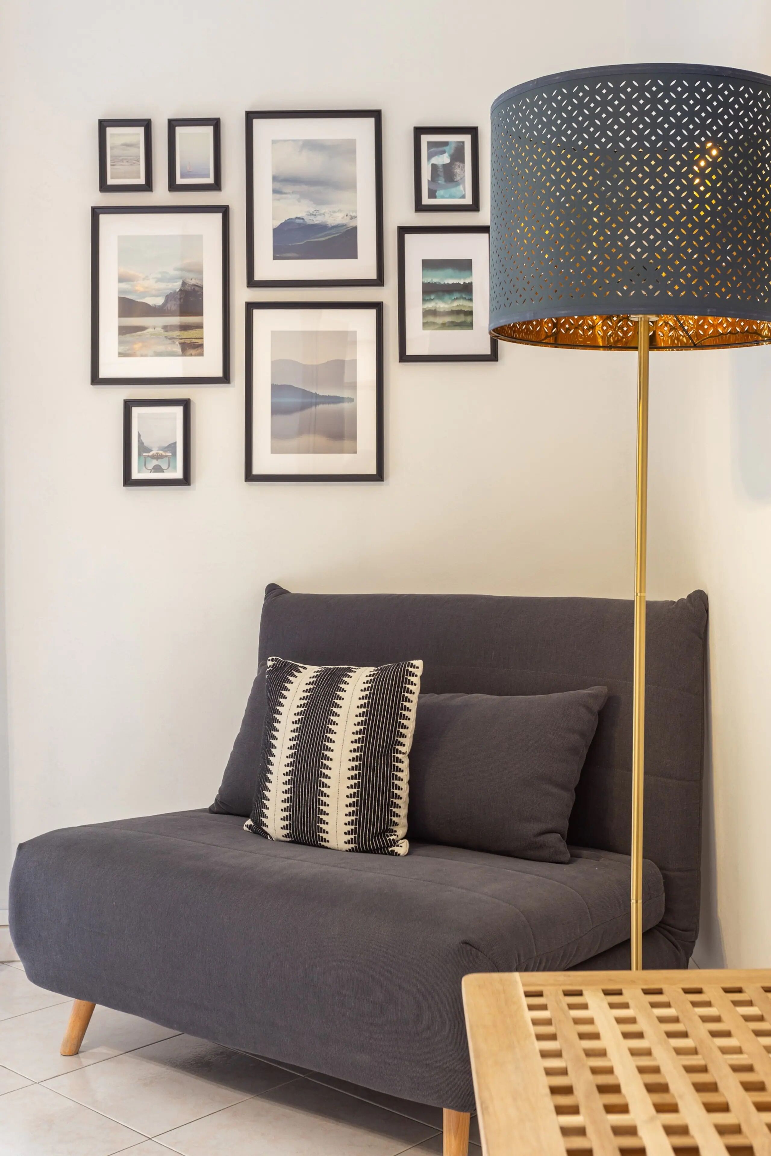 Un salon moderne avec un canapé gris, un coussin décoratif à motifs et une lampe sur pied.