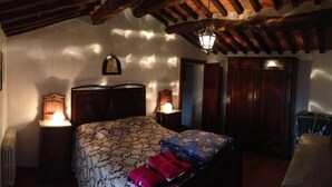 Quarto com cama, abajures, cabeceira de madeira, mesa de cabeceira e guarda-roupa.