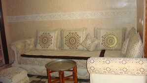 Ein Sofa mit gemustertem Kissen, ein passendes Ottomanen und ein kleiner Holztisch.
