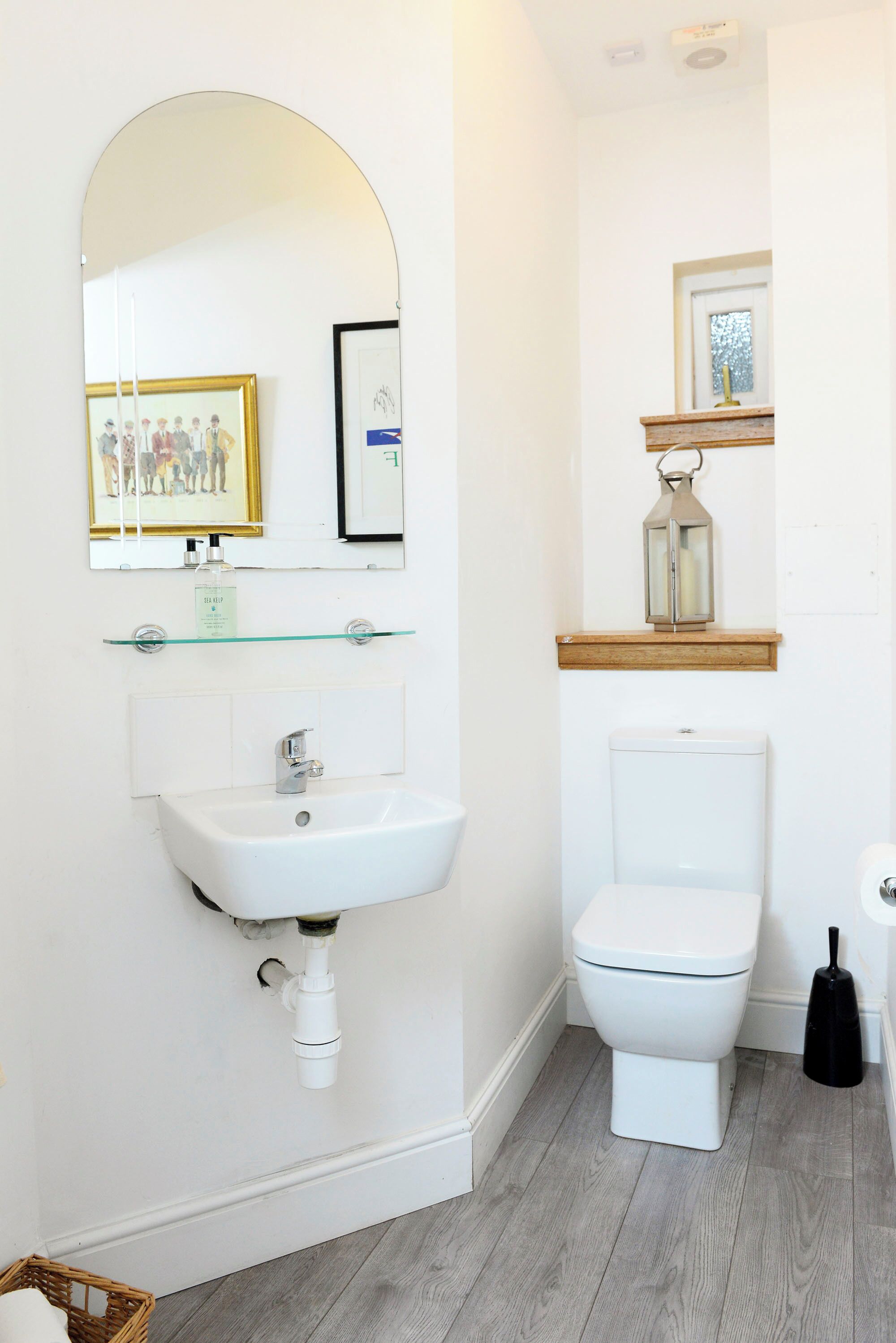 Ein Badezimmer mit Waschbecken, Toilette, Spiegel und einem gerahmten Bild an der Wand.