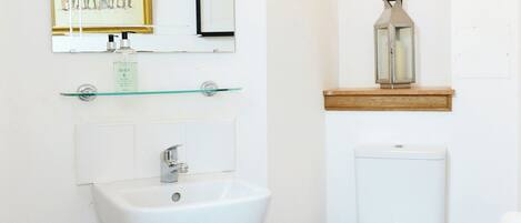 Ein Badezimmer mit Waschbecken, Toilette, Spiegel und einem gerahmten Bild an der Wand.