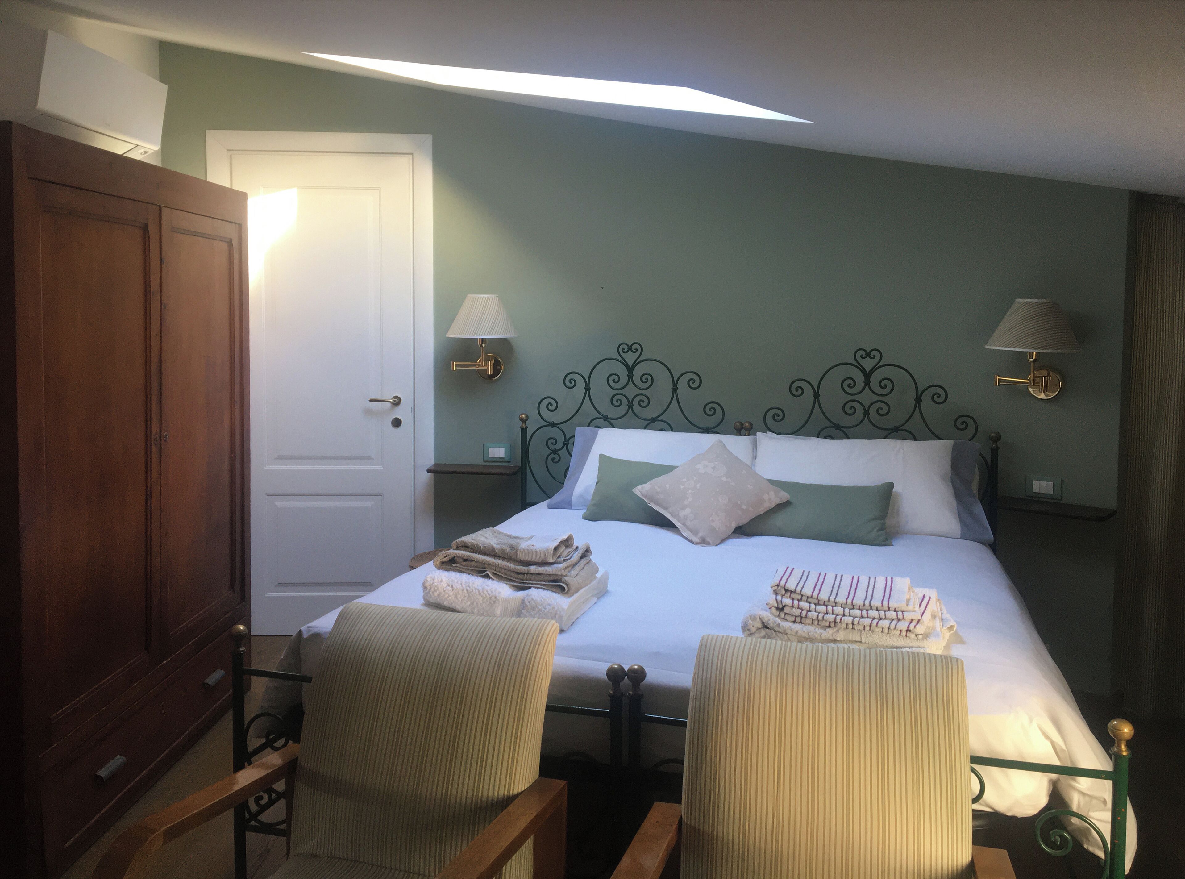 Ein ordentlich eingerichtetes Schlafzimmer mit einem Bett, zwei Stühlen, einem Kleiderschrank und Nachttischlampen.
