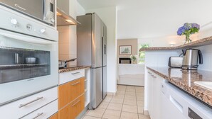 A modern kitchen with a built-in oven, a refrigerator, and a coffee maker on the countertop. - Profitez de votre piscine privée + accès golf (Moliets)
