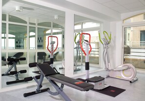 A gym with exercise equipment, a bench, and a mirrored wall.