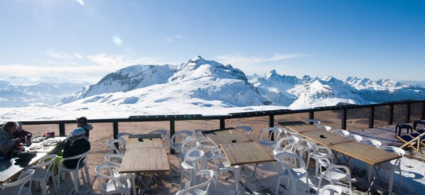 A snow-covered mountain view with outdoor seating and tables.