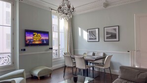 Una sala de estar moderna con un televisor de pantalla plana, una mesa de comedor con sillas, un sofá y una mesa auxiliar.