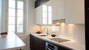 Una cocina moderna con muebles blancos, un lavamanos doble y un horno empotrado.