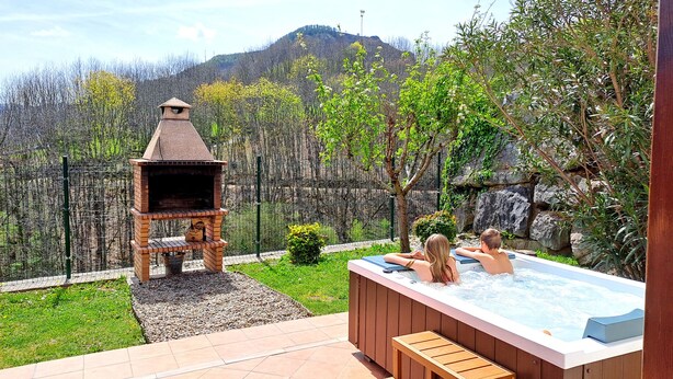A backyard with a brick barbecue, a hot tub, and a view of a mountain. - Luxe studio Casa Angiz Etxea 2; charm, outdoor spa and valley views (Sunbilla)