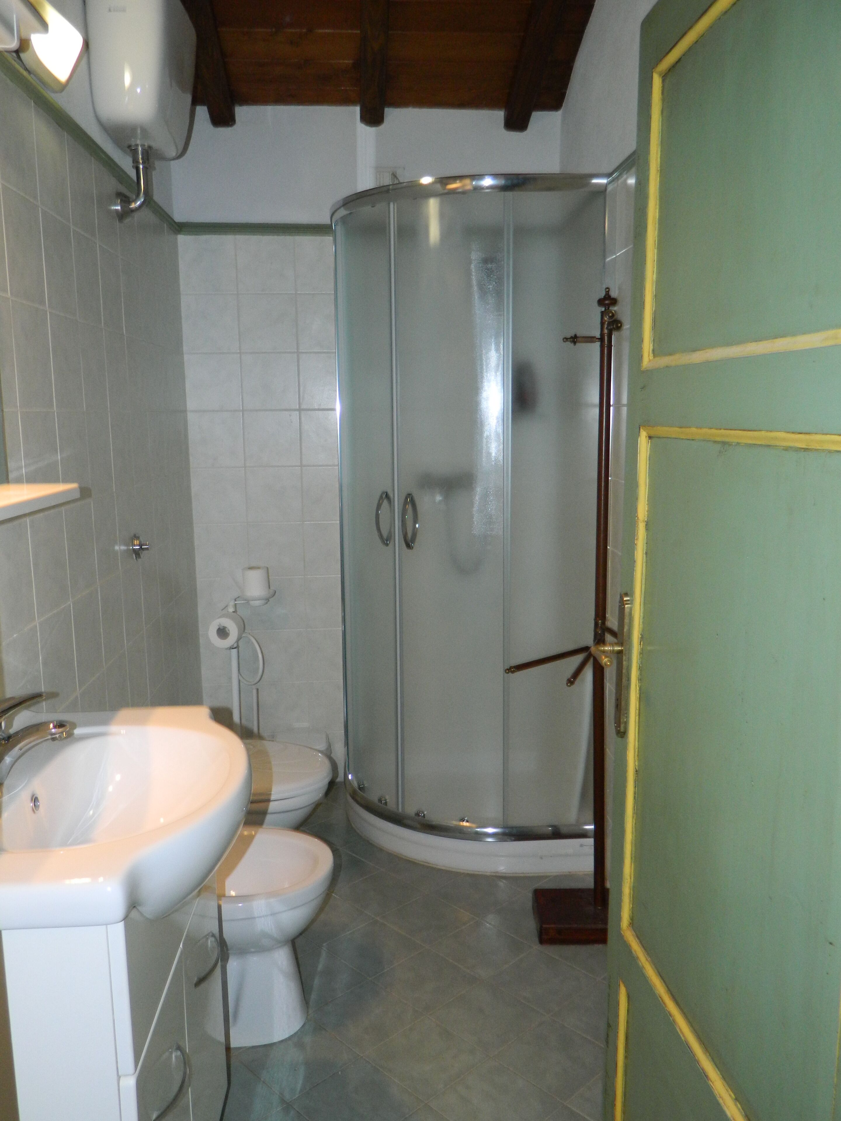 Een badkamer met douche, toilet en wastafel.