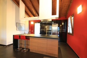 A modern kitchen with a central island, bar stools, and stainless steel appliances.