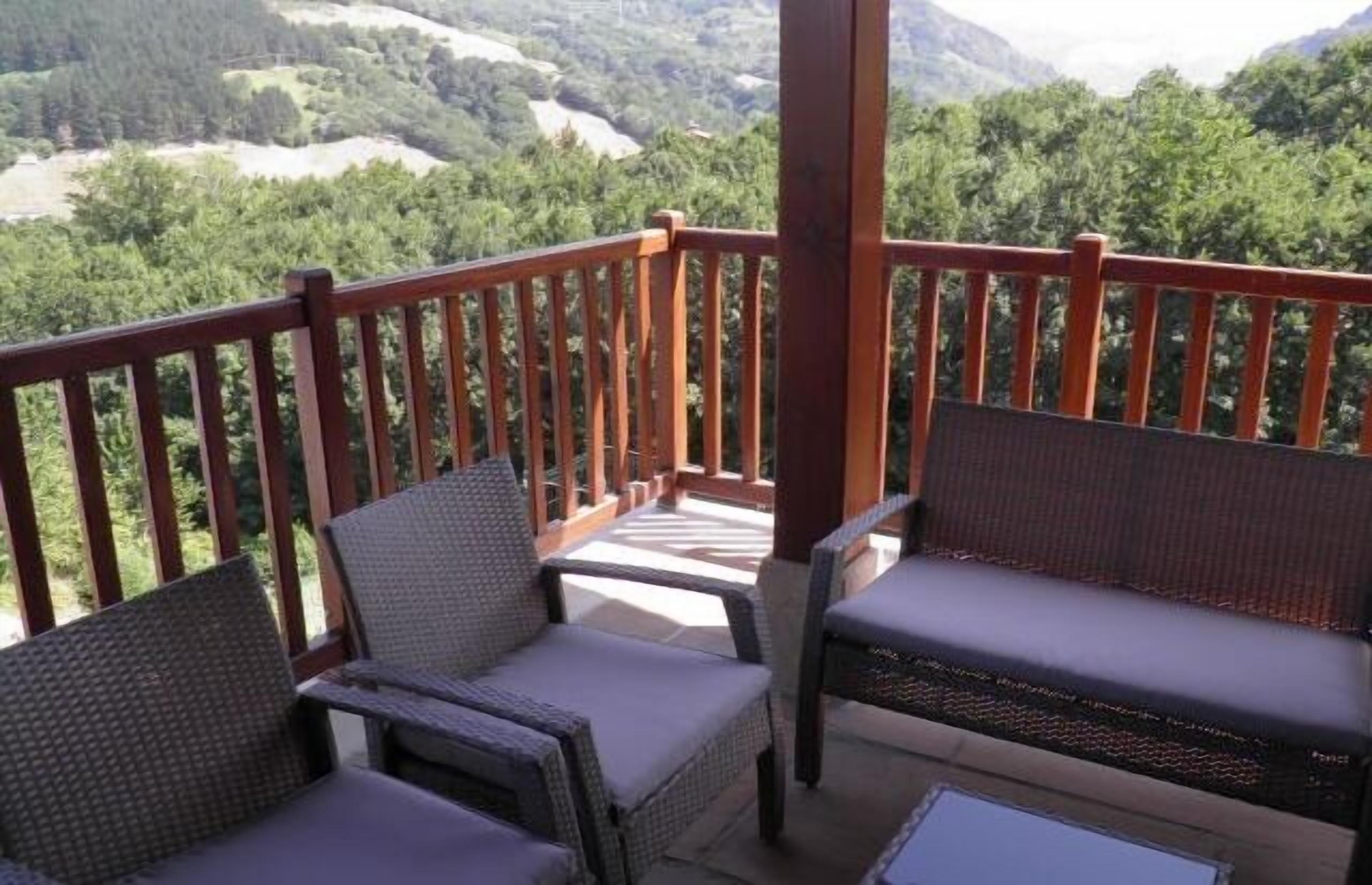 Een balkon met rieten meubilair en uitzicht op een bergachtig landschap.