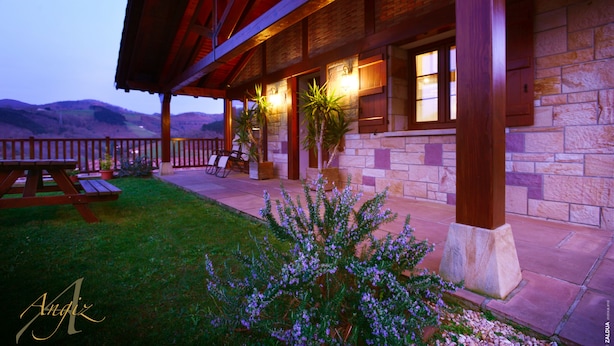 A stone building with a covered patio, outdoor seating, and a view of the mountains. - Charming apartment with mountain views for 4 people, Casa Angiz Etxea 1 (Sunbilla)