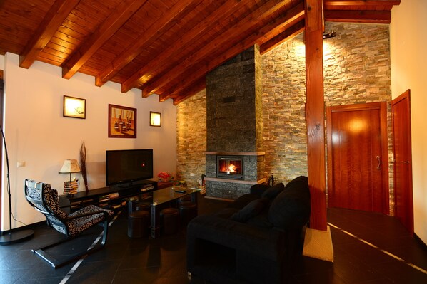 A cozy living room with a fireplace, a sofa, a TV, and a dining area.