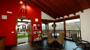 A room with a red wall, a wooden ceiling, a balcony with a view, wicker furniture, and a 'SALIDA' sign. - Charming apartment with mountain views for 4 people, Casa Angiz Etxea 1 (Sunbilla)