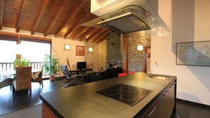 A modern kitchen with a built-in stove, wooden ceiling beams, and a stone wall. - Charming apartment with mountain views for 4 people, Casa Angiz Etxea 1 (Sunbilla)