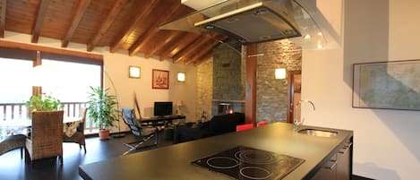 Una cocina moderna con estufa integrada, vigas de techo de madera y pared de piedra.