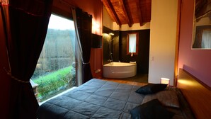 A bedroom with a large bed, a bathtub, and a view of a forest. - Charming apartment with mountain views for 4 people, Casa Angiz Etxea 1 (Sunbilla)